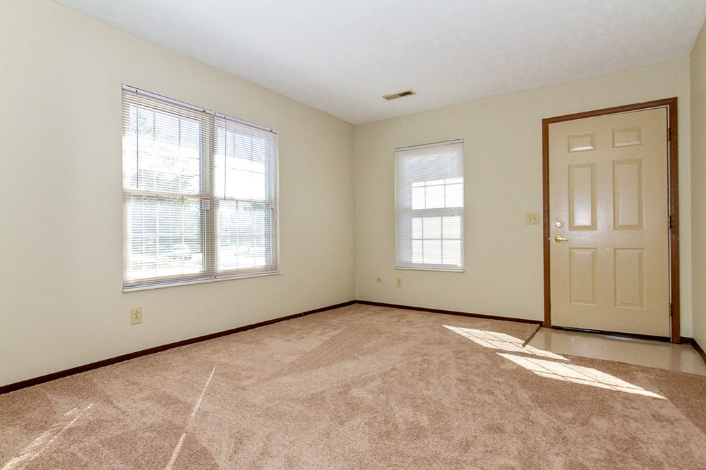 the living room of an empty house with a door and window