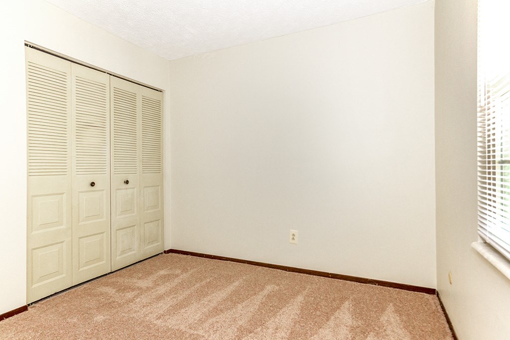 an empty room with a closet and a window