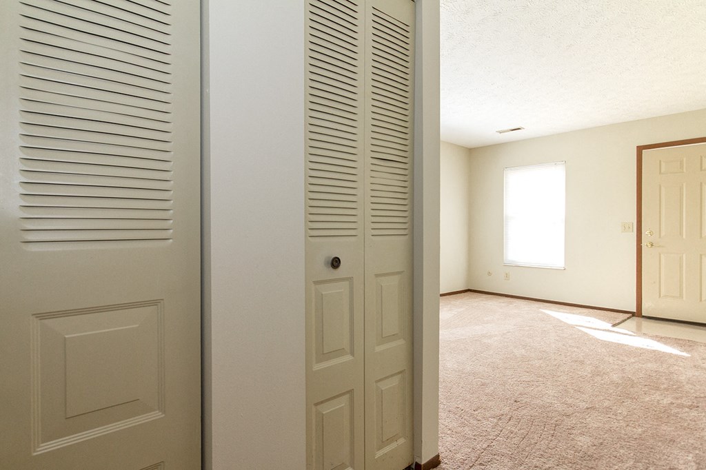 an open door into a living room with a door to a closet