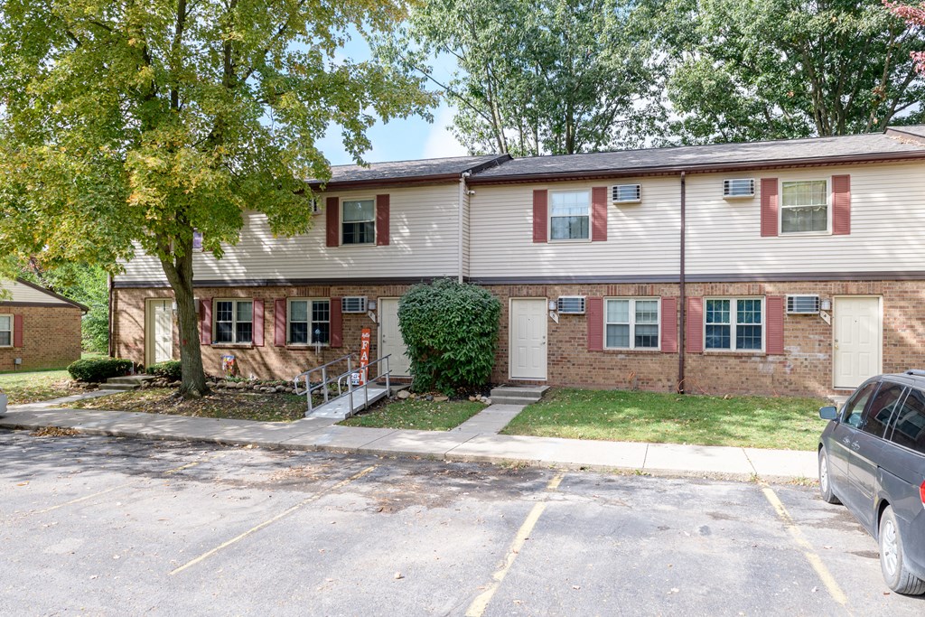 front view of a white house with red shutters and a tree
