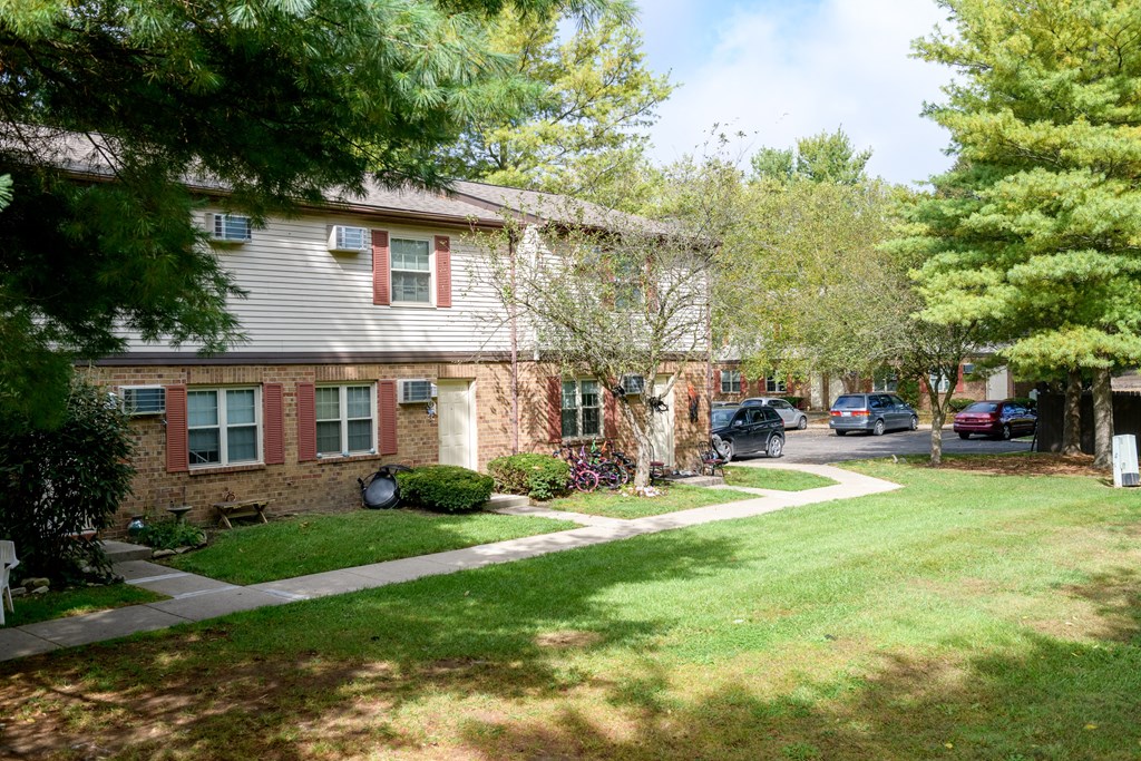 the front of a brick house with a lawn and trees