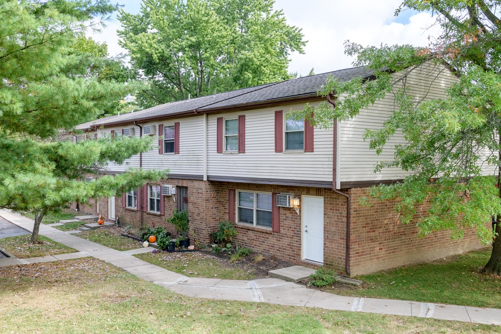 the front of a brick house with a white roof and a sidewalk