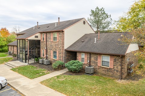 a brick house with a glass screened porch and a lawn