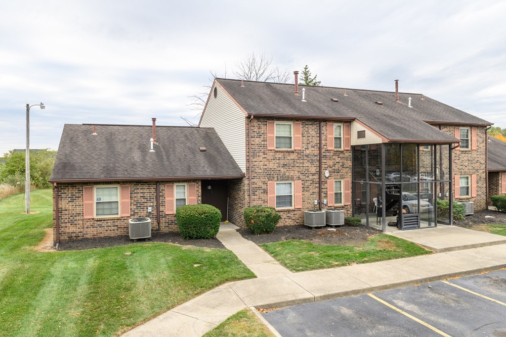 the front of a brick house with a glass walkway and grass