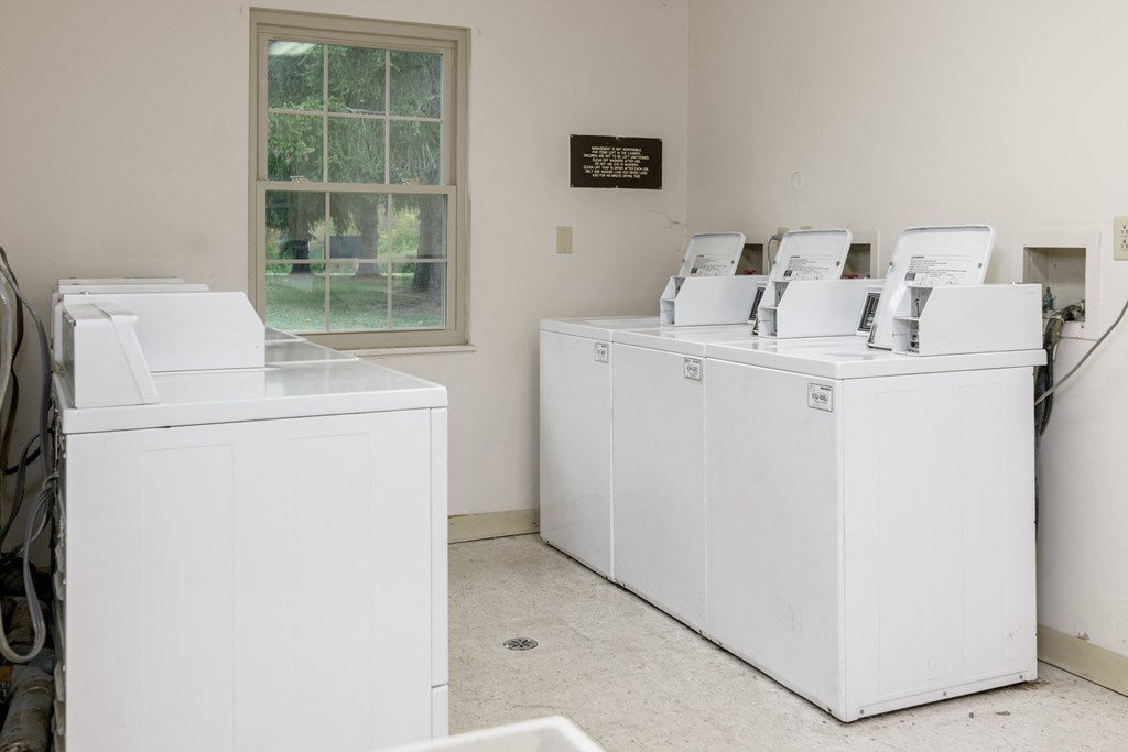 four washers and dryers in a room with a window