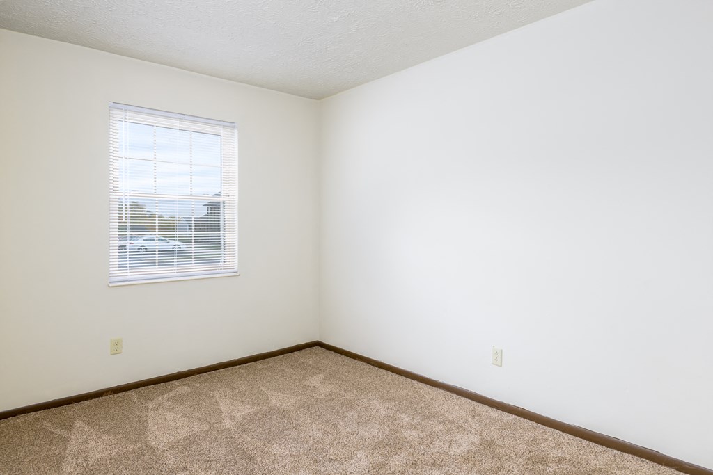 an empty room with a window and white walls