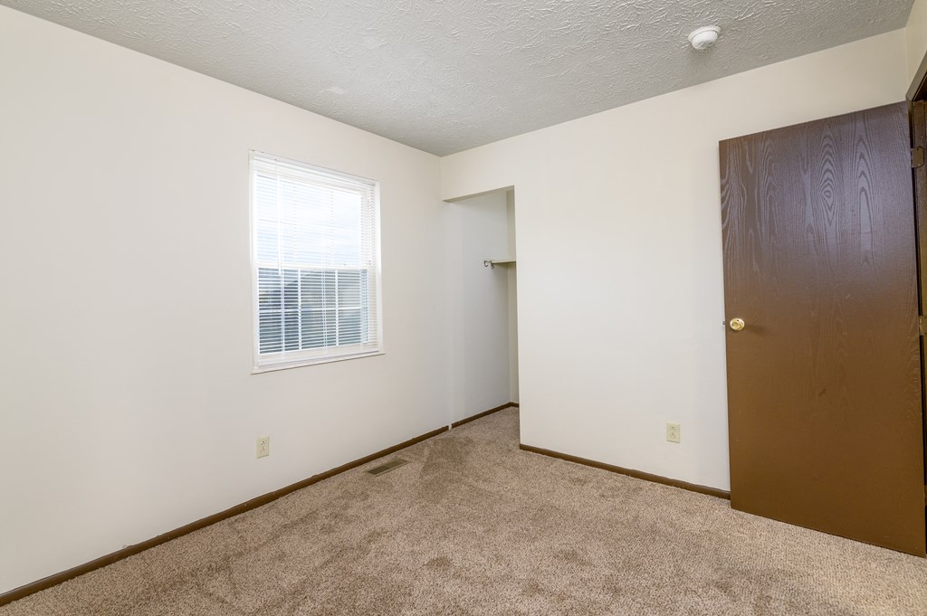 a bedroom with a door and a window and a carpeted floor