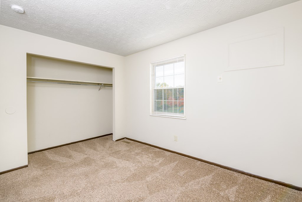 an empty room with a closet and a window