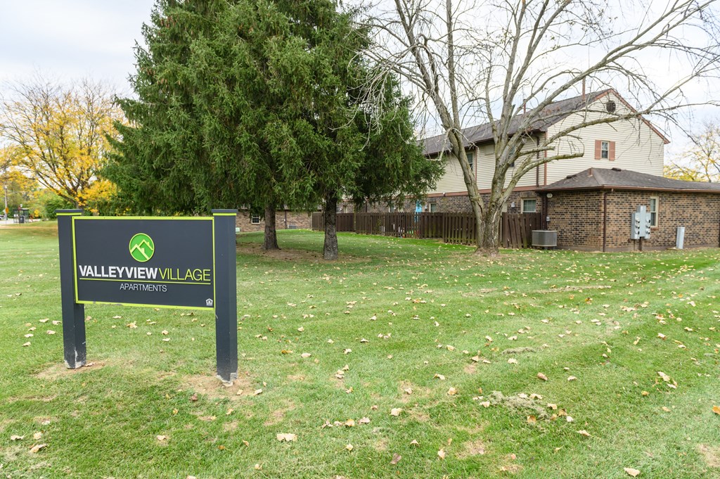 a sign in the grass in front of a house