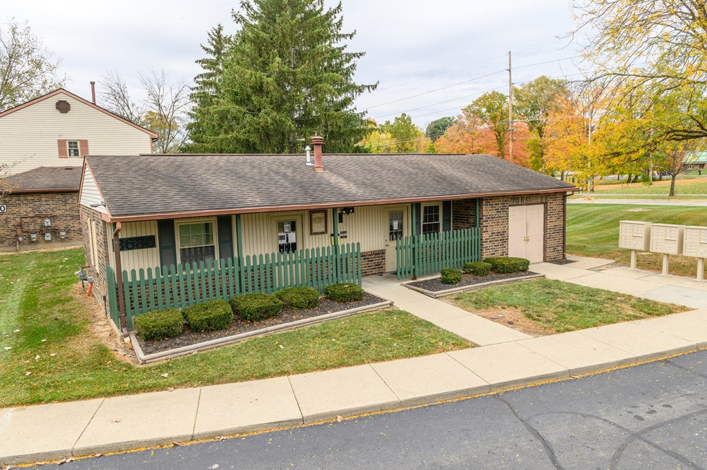 a small white house with a green fence and a sidewalk