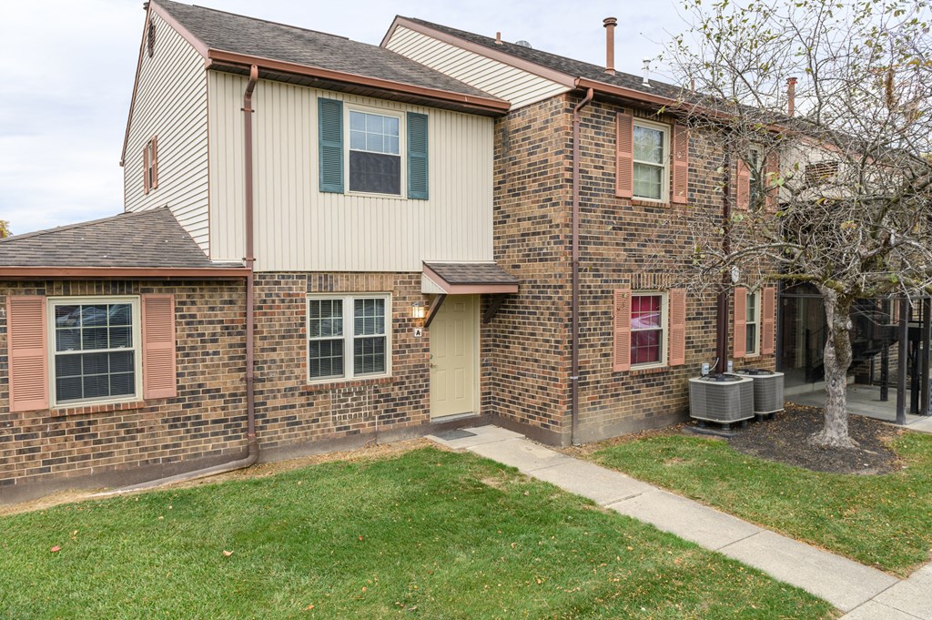 the front of a brick house with a sidewalk and grass