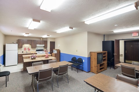 a multipurpose room with tables and chairs and a kitchen