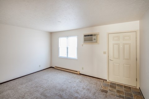the living room of an empty house with a door and a air conditioner