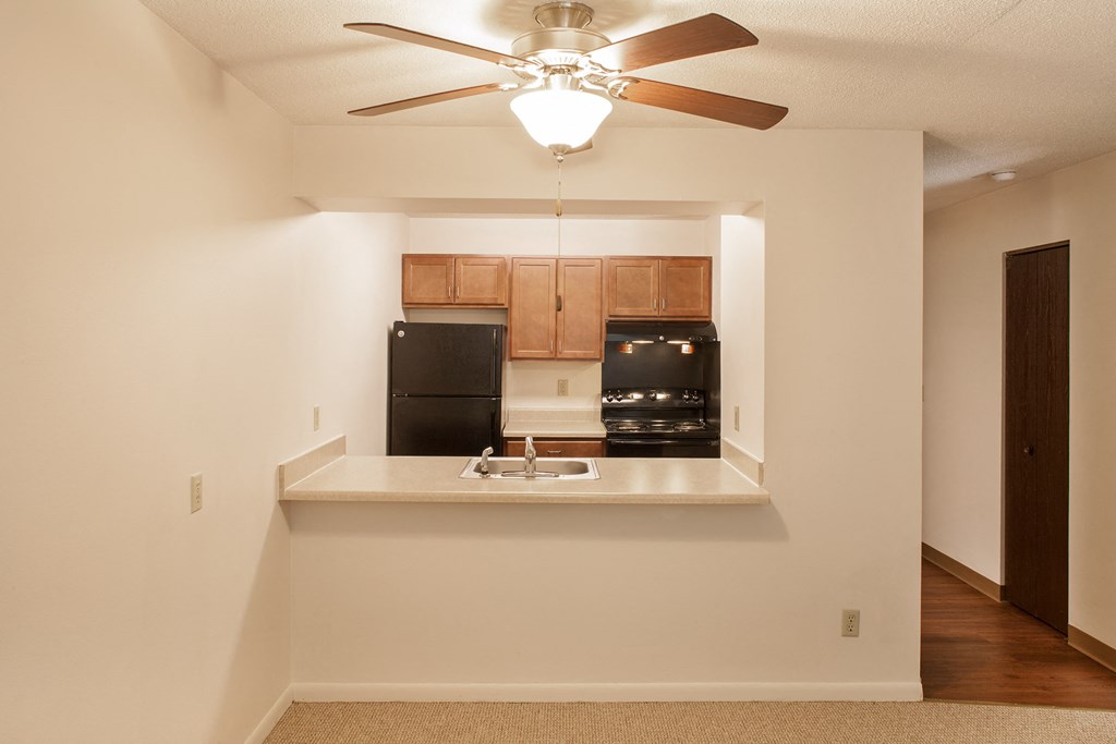 an empty kitchen with a ceiling fan and a sink