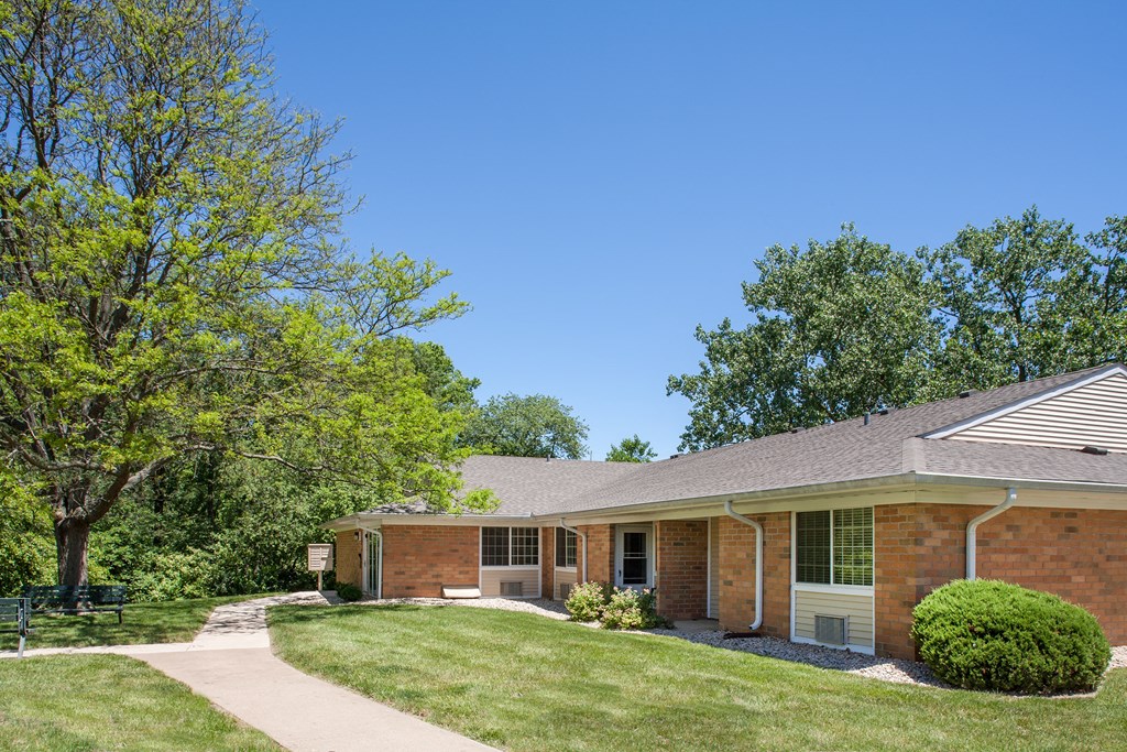 a brick house with a lawn and trees