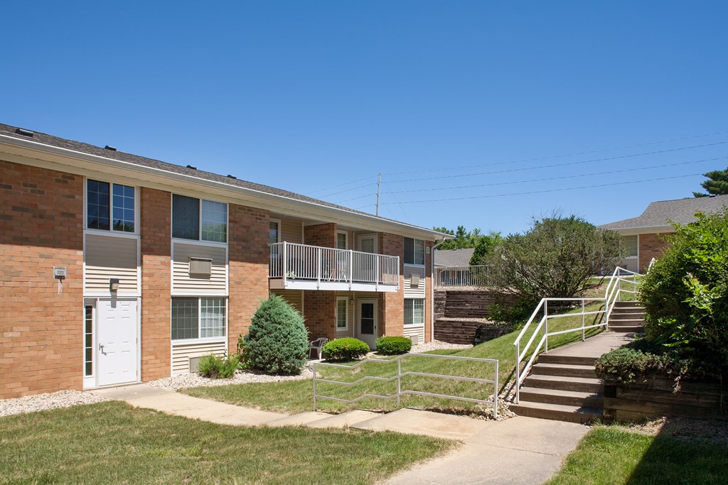 an exterior view of a brick apartment building with stairs and a sidewalk