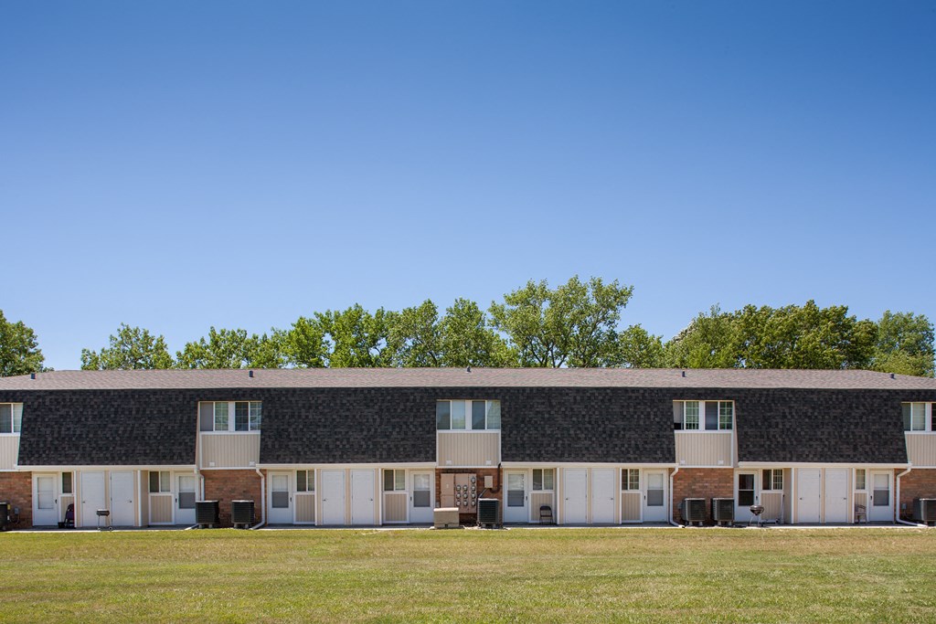 a building with a black and white facade and a green field