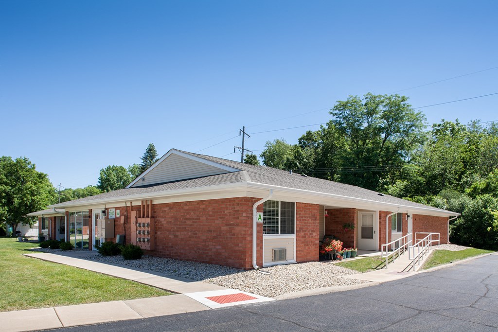 the front of a brick building with a porch and stairs