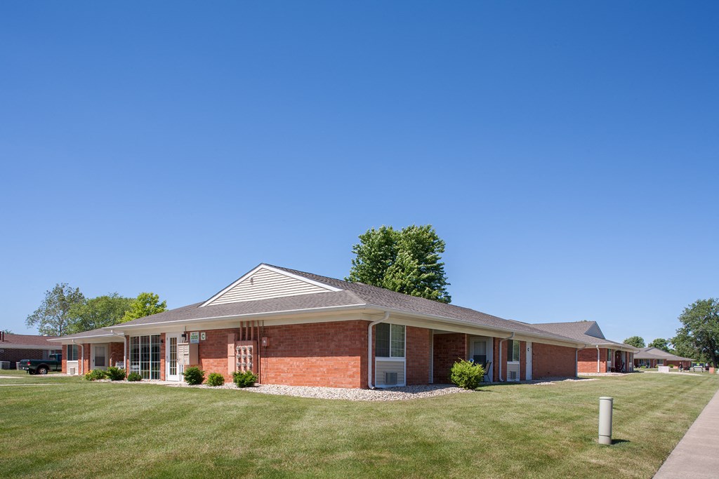 a brick building with a lawn and a blue sky