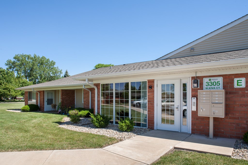 the front of a brick building with glass windows and a sidewalk