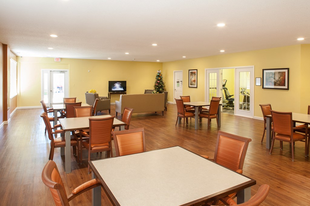 a dining room with tables and chairs and a living room with a television