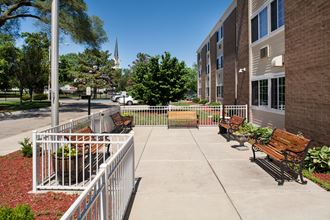 an outdoor patio area with benches in front of an apartment building