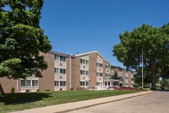 a large brick apartment building with a lawn and trees