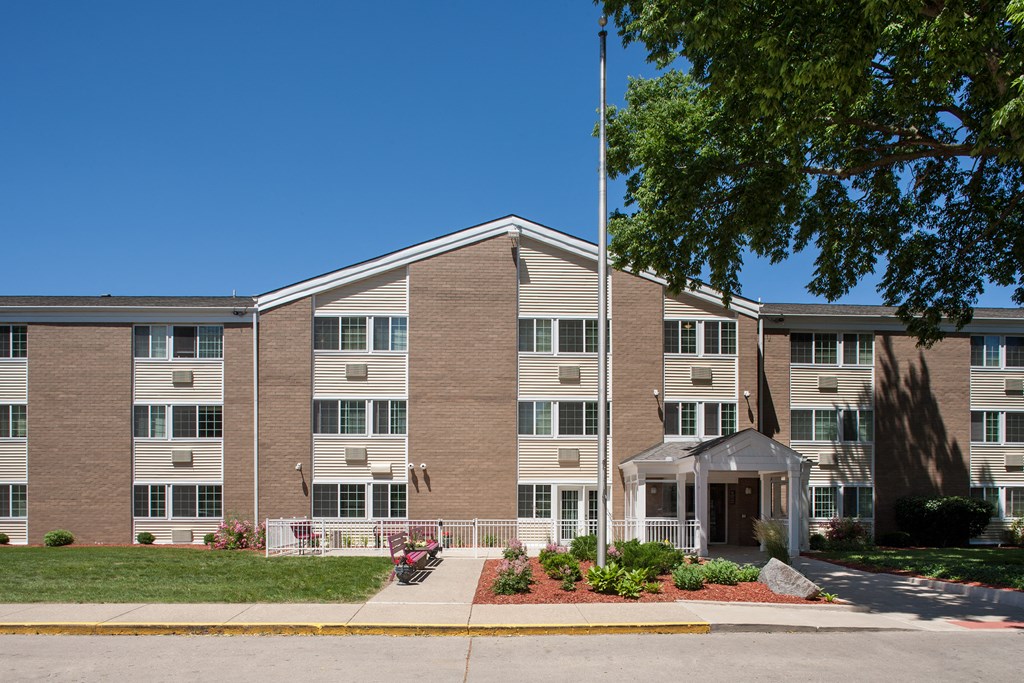 a large brick building with a flagpole and a tree