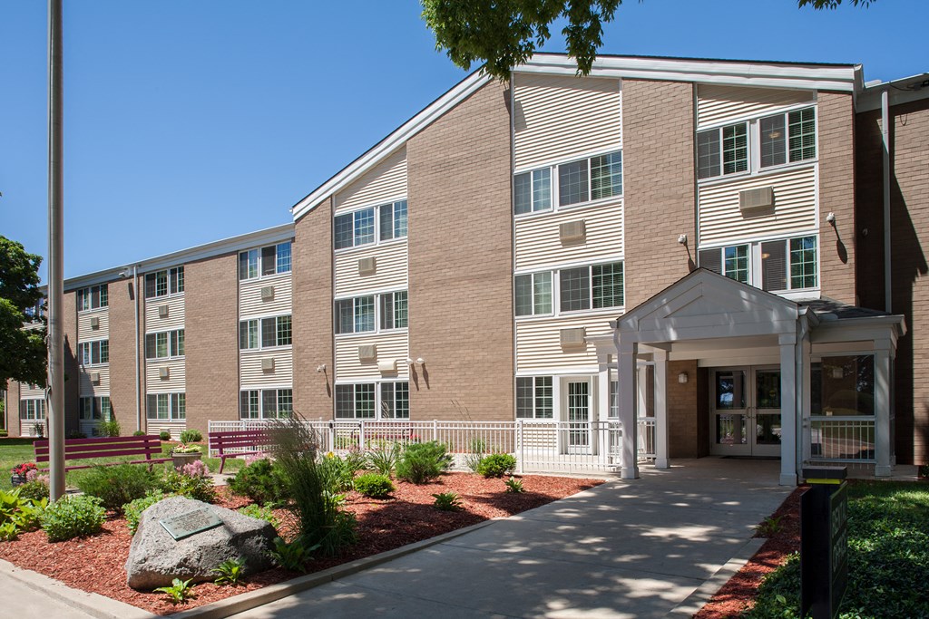 a large brick building with a porch and a sidewalk