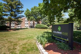 a sign sits in the grass in front of an apartment building
