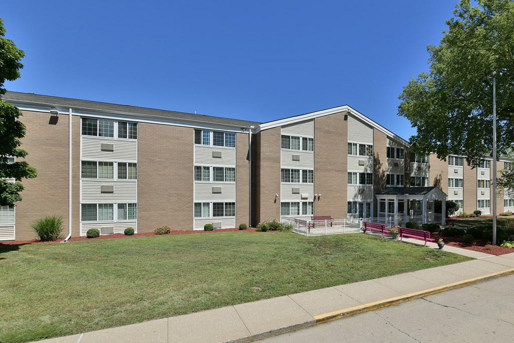 a brick apartment building with a lawn in front of it