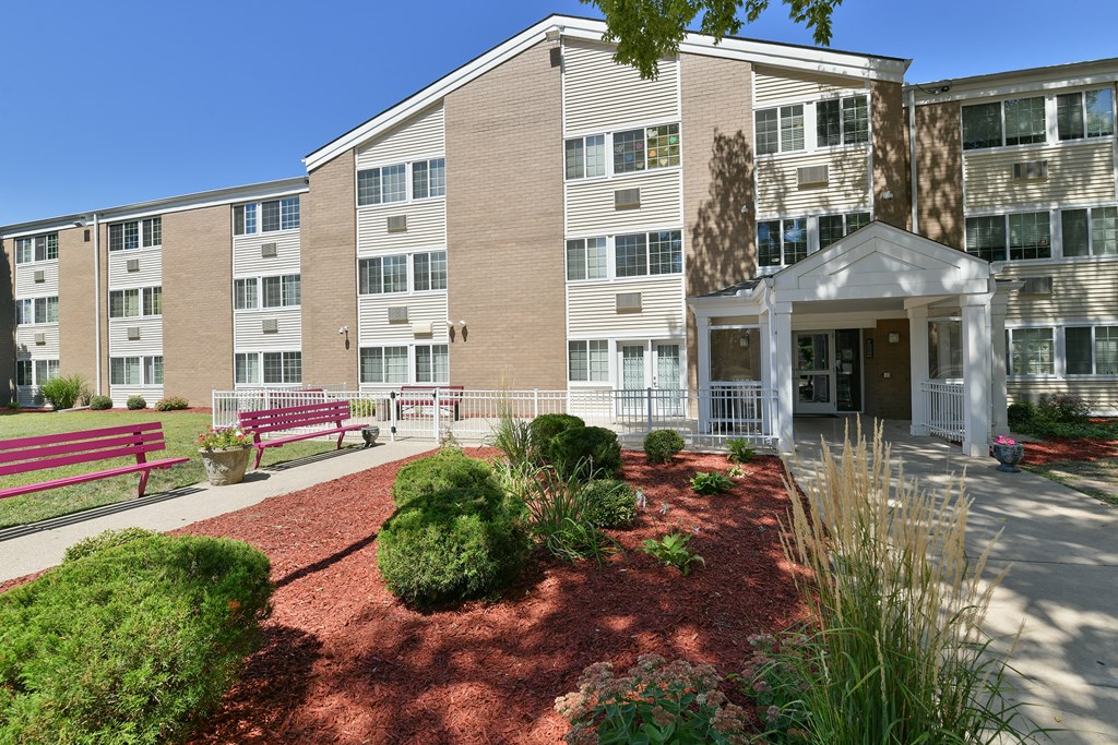 an exterior view of an apartment building with a courtyard and benches