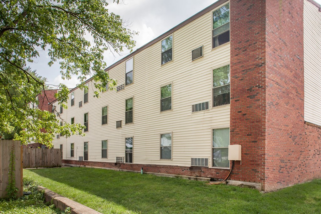 the exterior of an apartment building with a green lawn