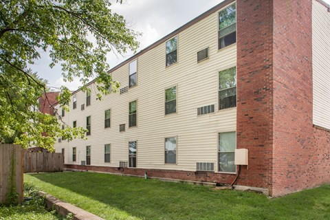 the exterior of an apartment building with a green lawn