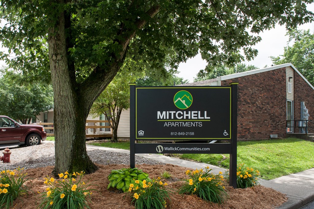 a sign apartments in front of a tree