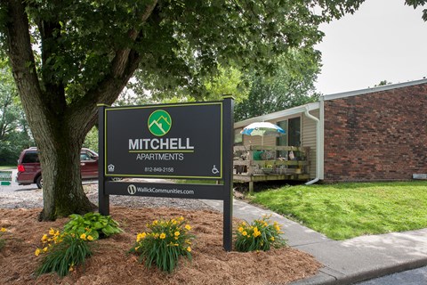 a sign apartments in front of a tree