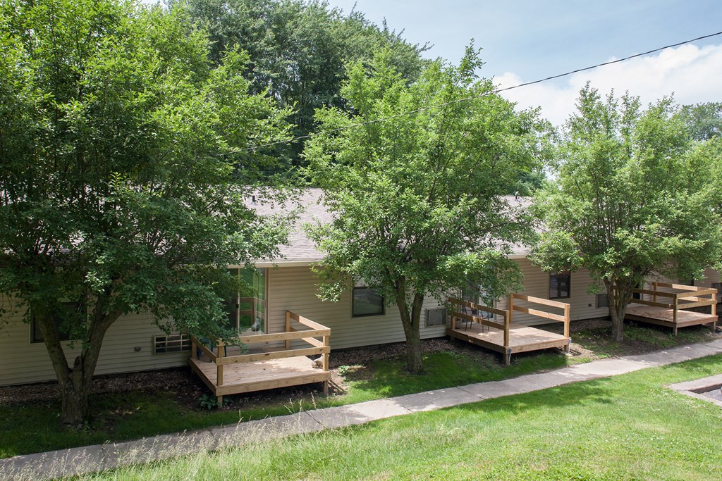 the home has a deck and trees in front of it