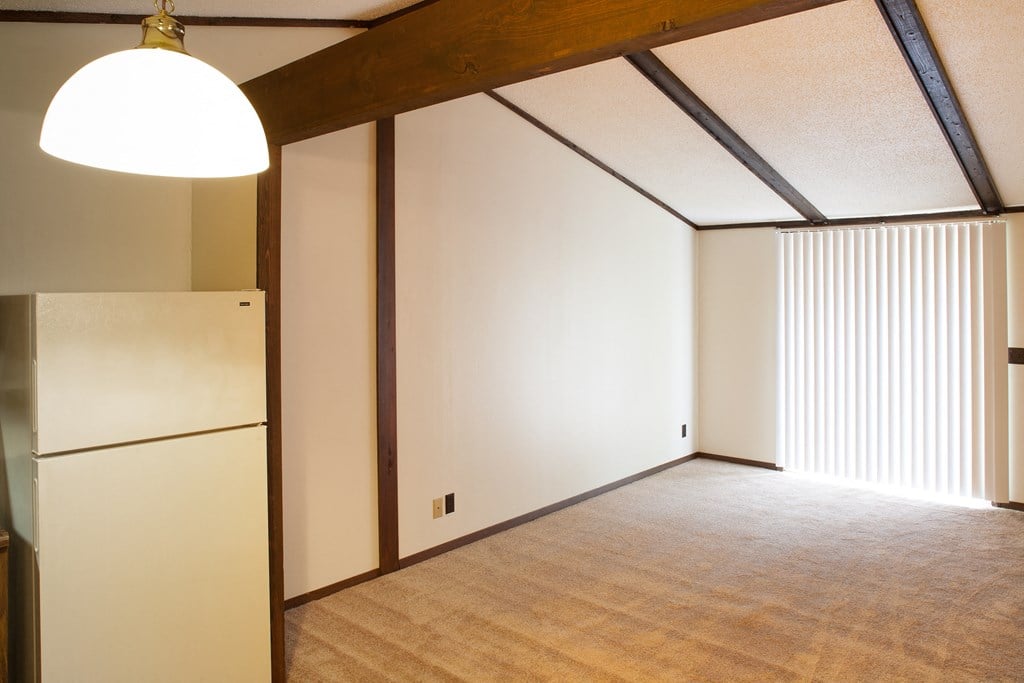 a living room with white walls and a refrigerator