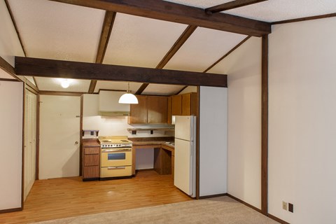 a kitchen with wooden floors and white walls and a white refrigerator