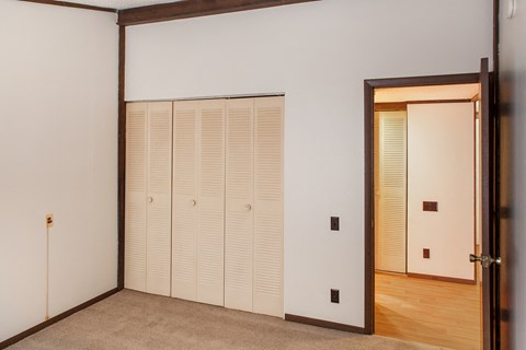 a bedroom with white walls and a door to a closet