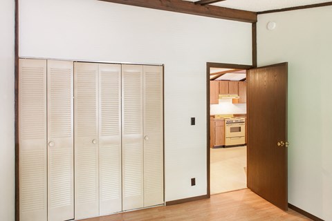 a bedroom with a closet and a door to a kitchen