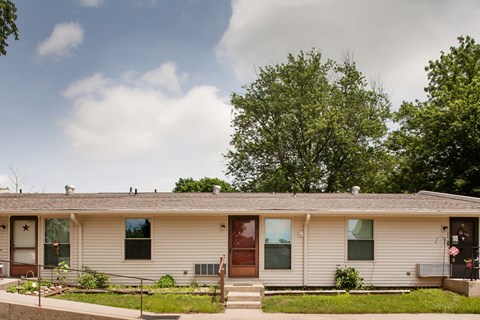 the front of a white house with a brown door