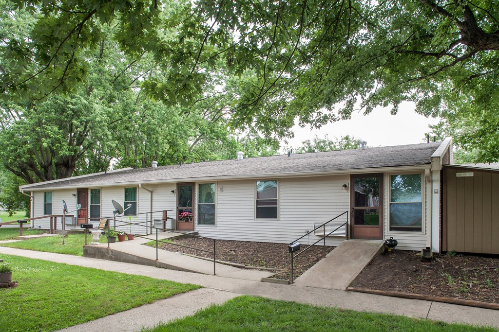 a small white house with a porch and a tree