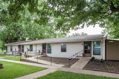 a small white house with a porch and a tree