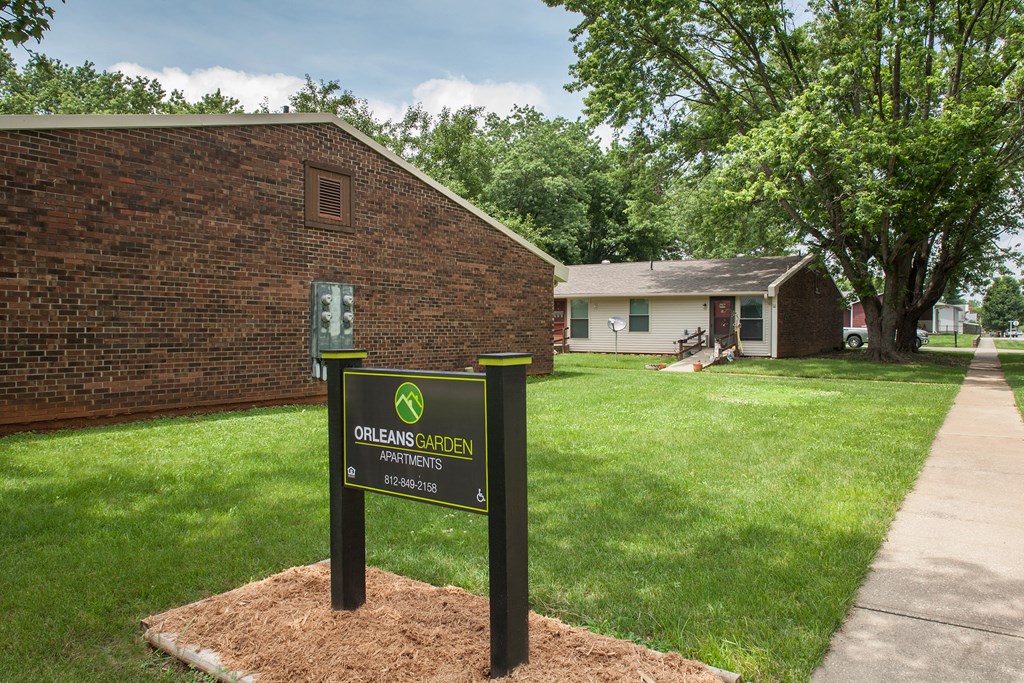 a green open house sign in front of a brick building
