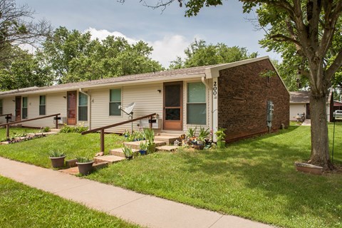 a small white house with a porch and a tree
