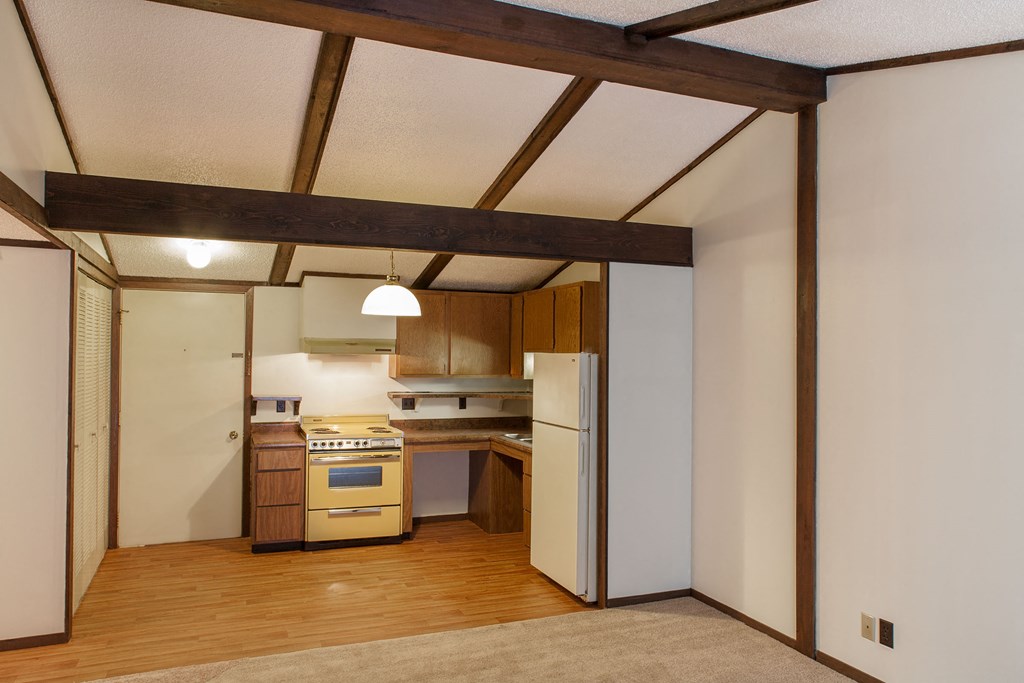 a kitchen with wooden floors and white walls and a white refrigerator