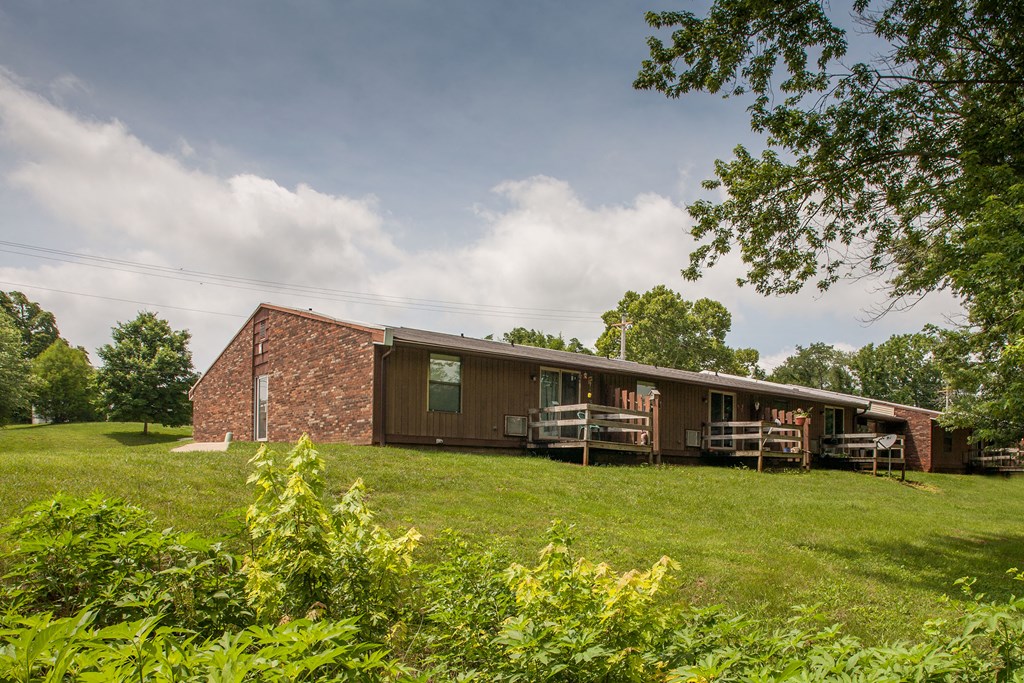 the front of a brick house with a porch and a grass yard