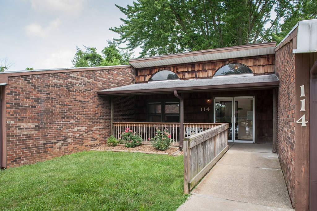 the front of a brick building with a porch and a glass door