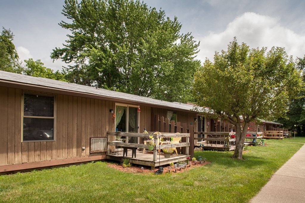 the front of a house with a porch and trees